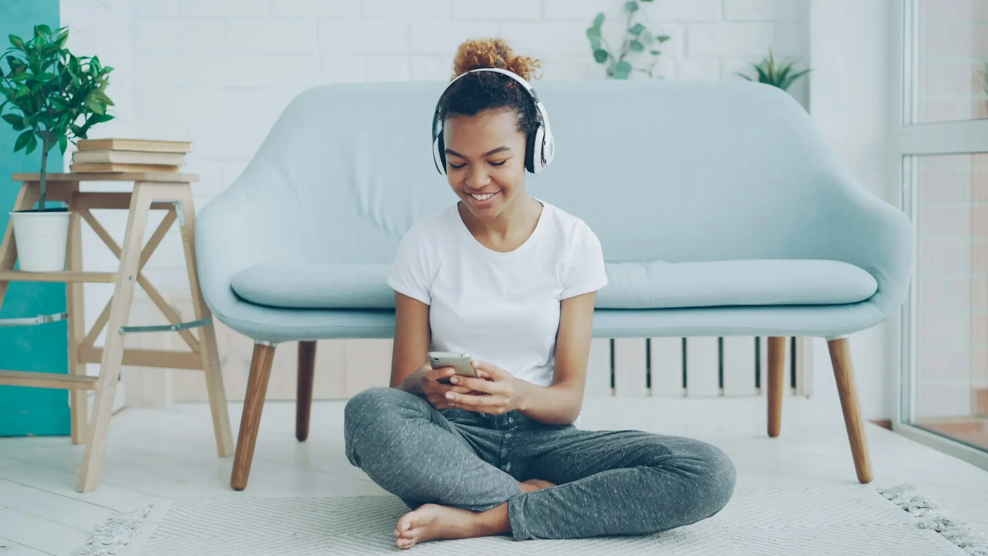 A woman sitting on the floor with headphones on, taking a quiet moment.