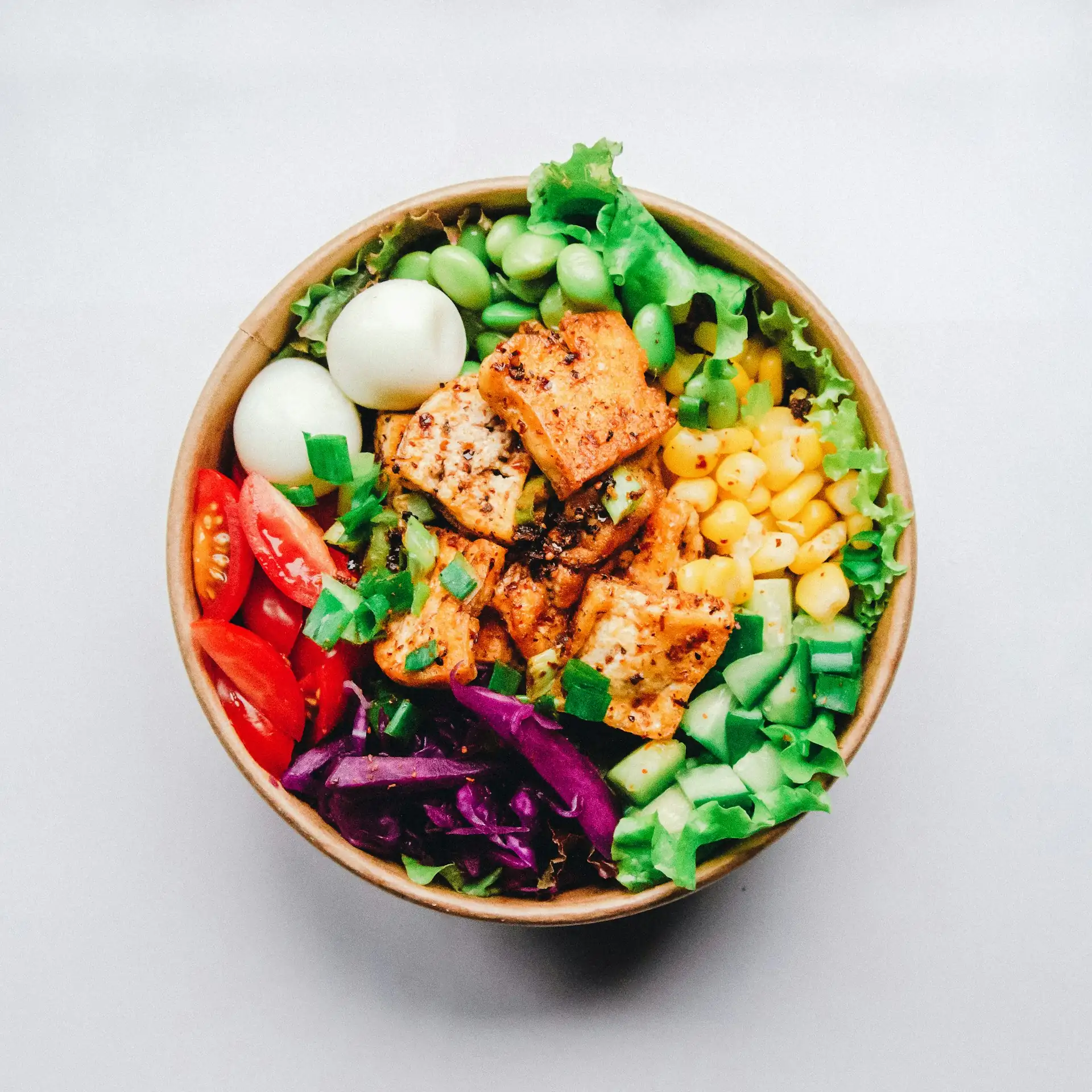 A vibrant bowl of vegetables and grilled protein, from above.