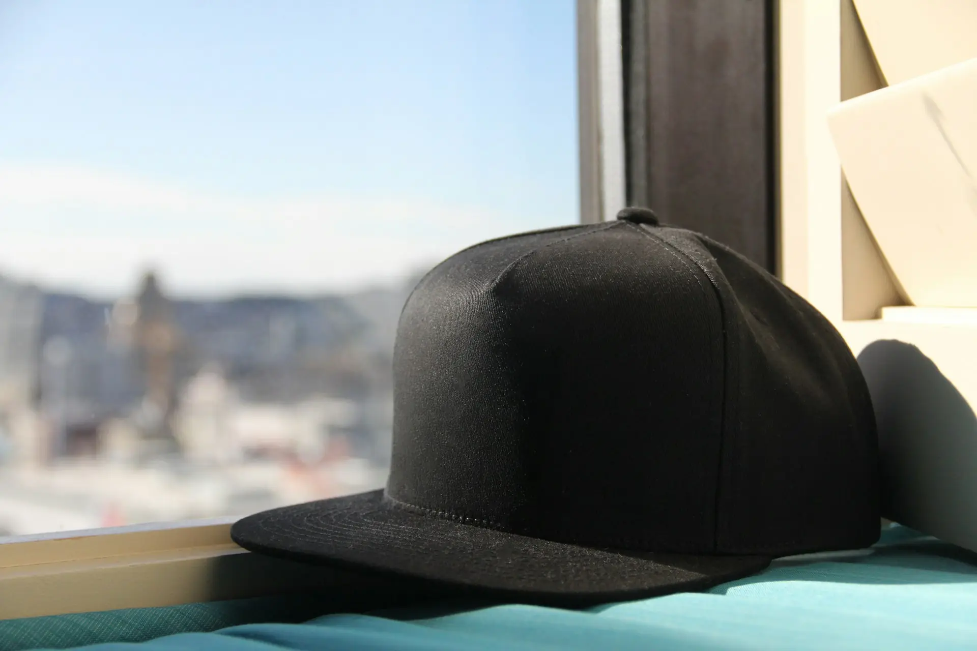 A plain black cap resting on a sunlit window sill.