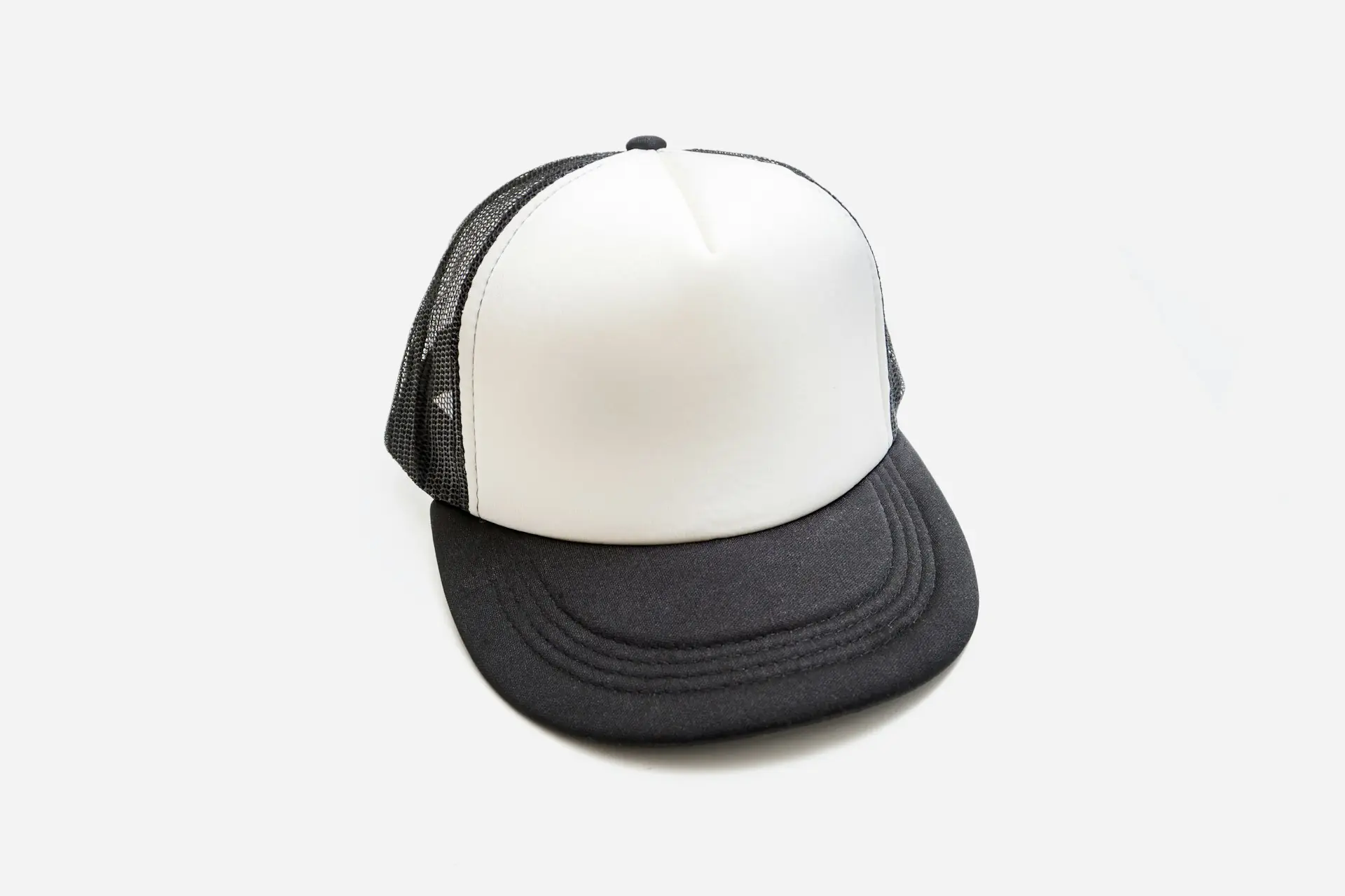 A black and white trucker cap on a white ground.