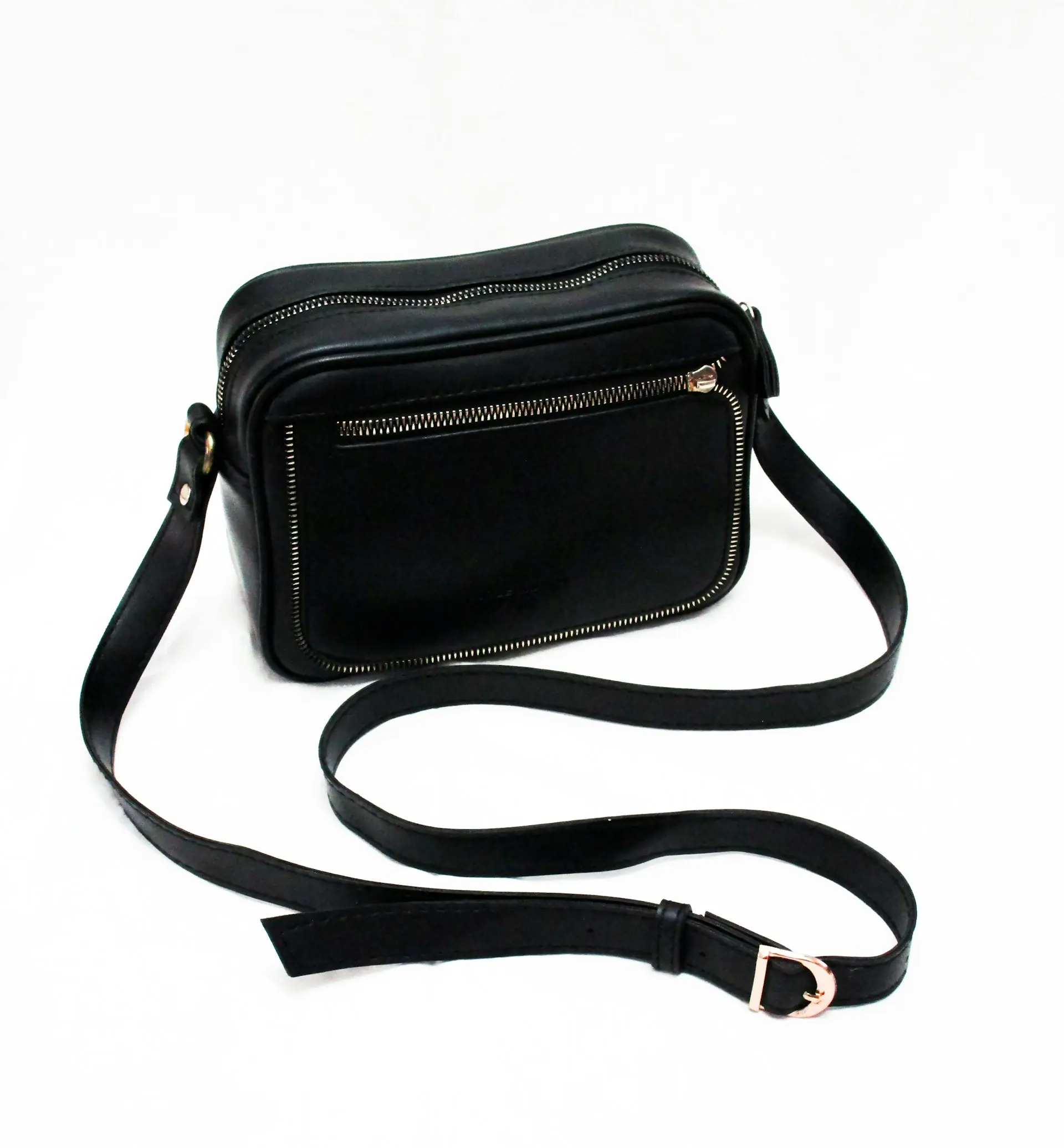 A black sling bag on a white surface.