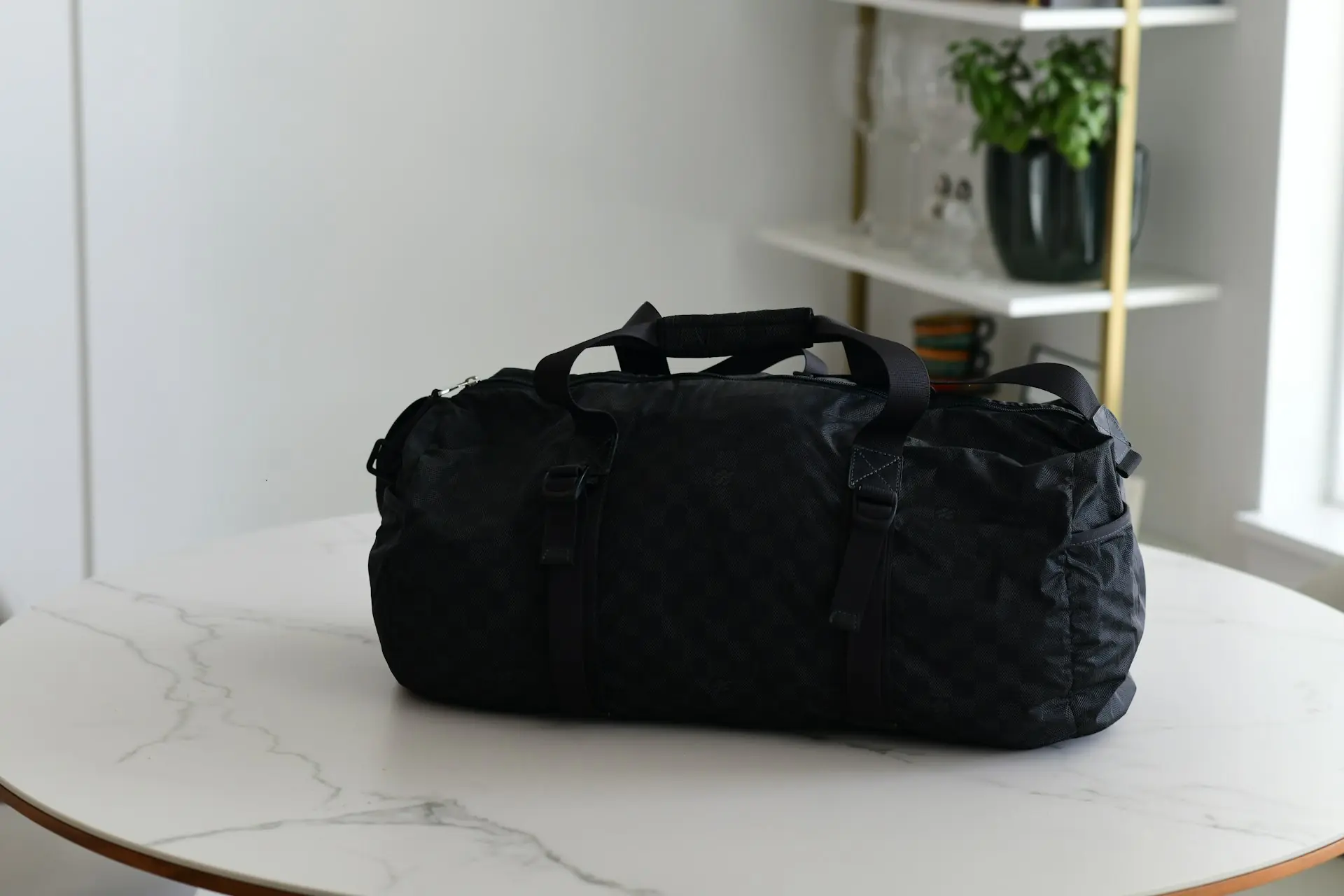 A black technical duffel on a marble table.