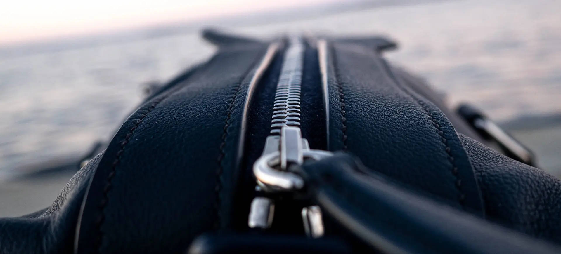 A black holdall zipper, up close at dusk.