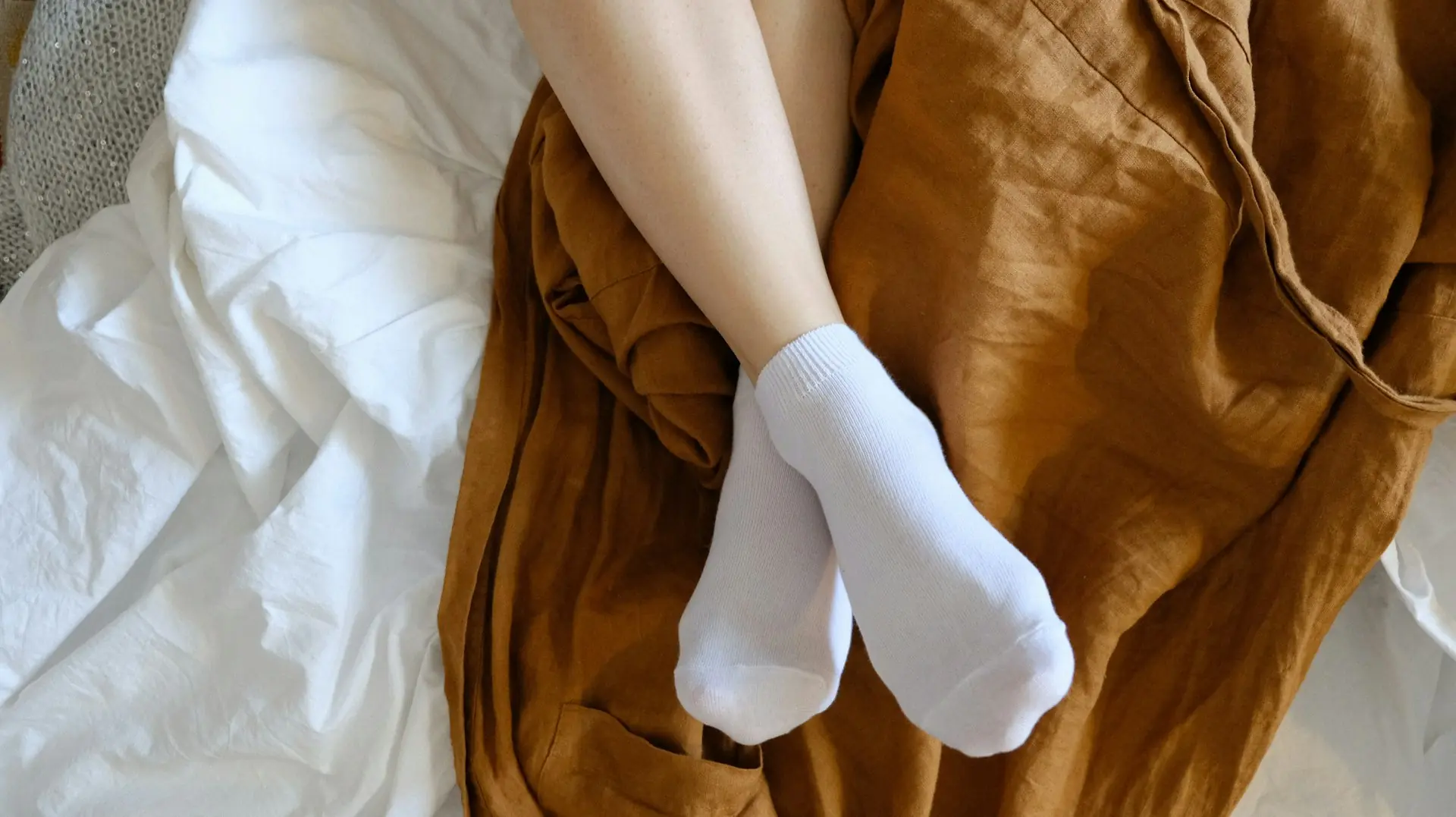 Soft white socks, feet up on the bed.