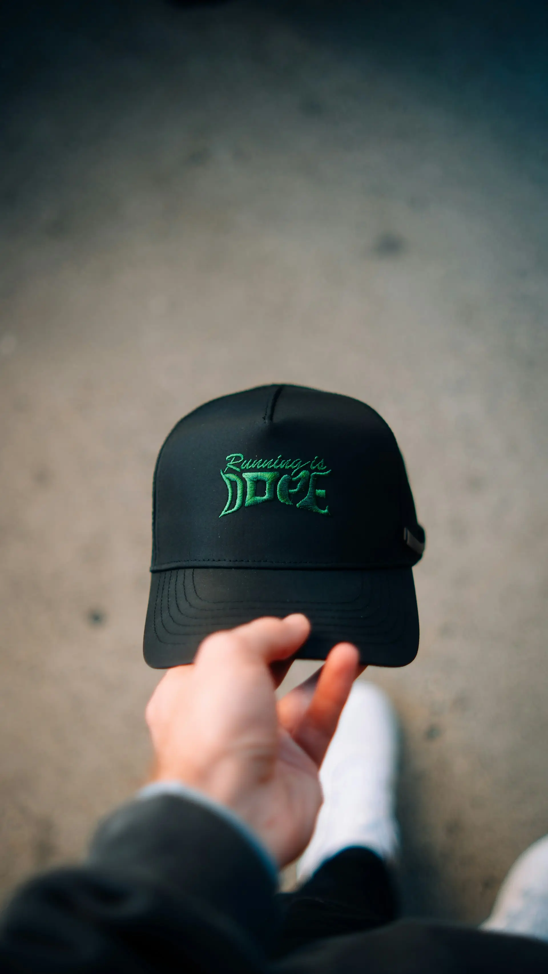 A black running cap held up against a concrete floor.