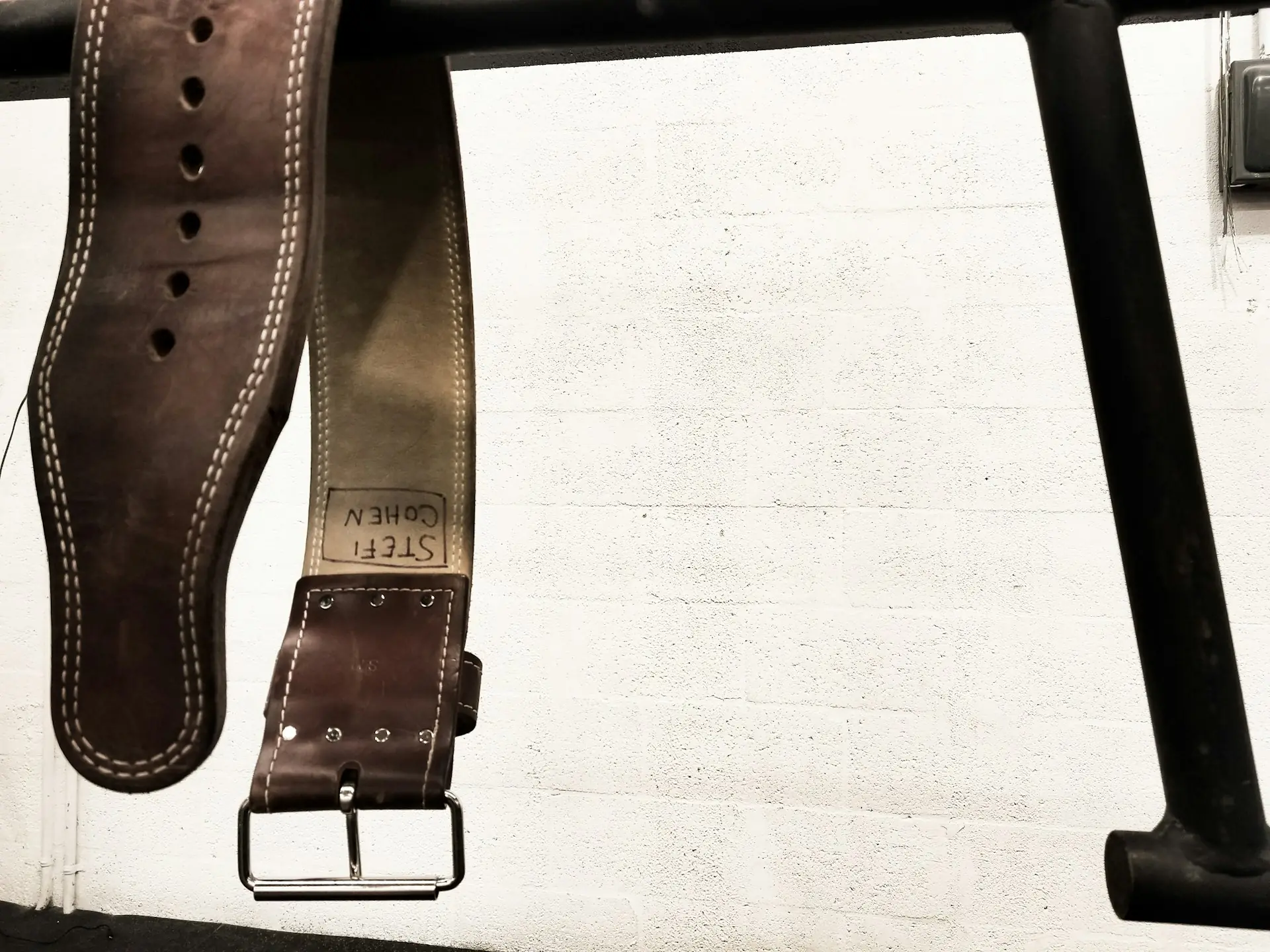 A brown leather strap coiled on white fabric.