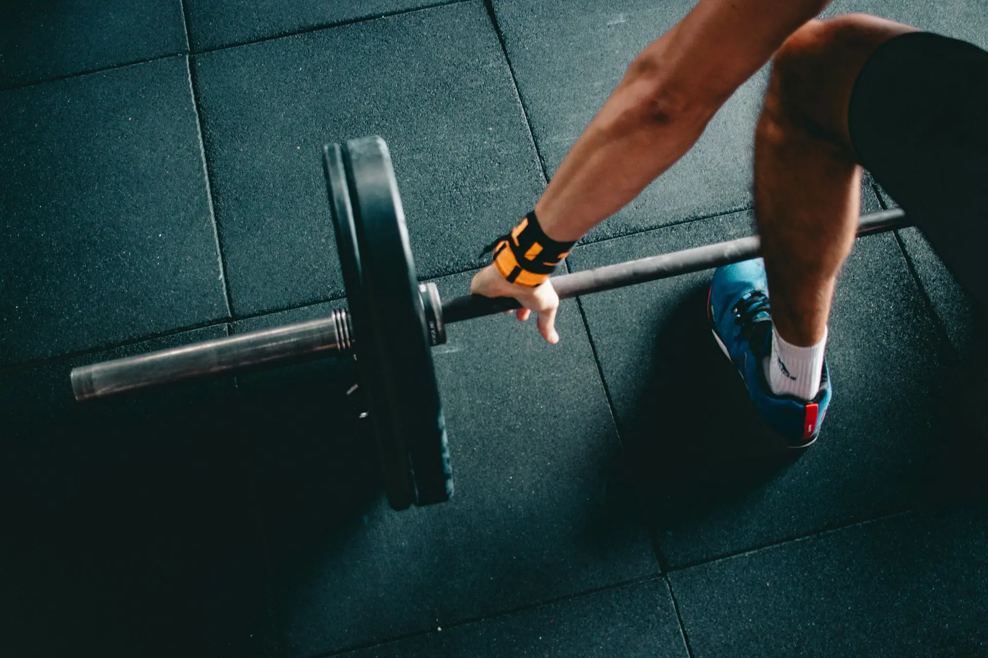 Orange wrist wraps at the barbell, from above.
