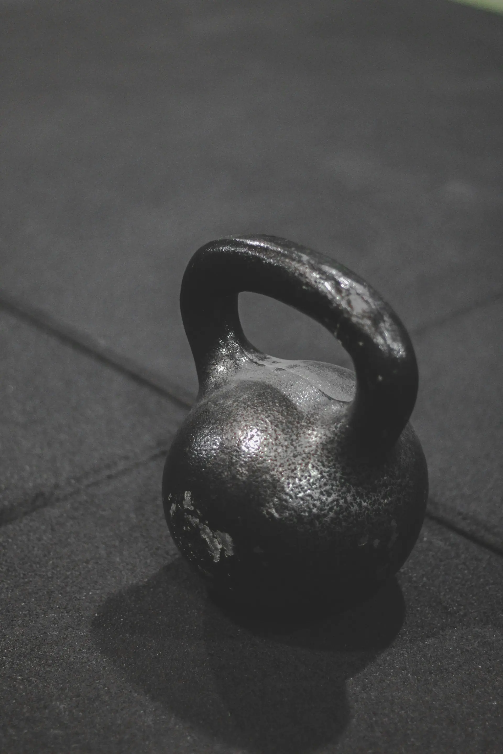 A chalk-dusted cast-iron kettlebell on a dark gym floor.