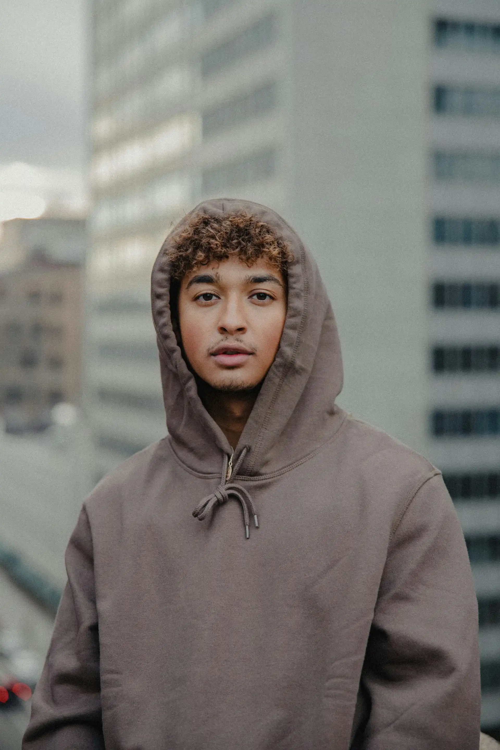A man in a grey hoodie in front of a white building.