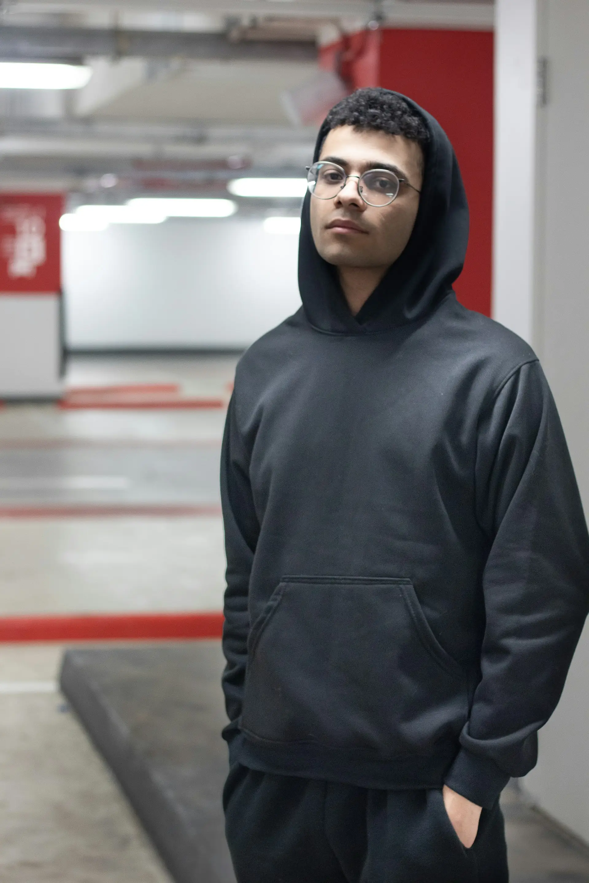 A man in a black hoodie in a concrete garage.