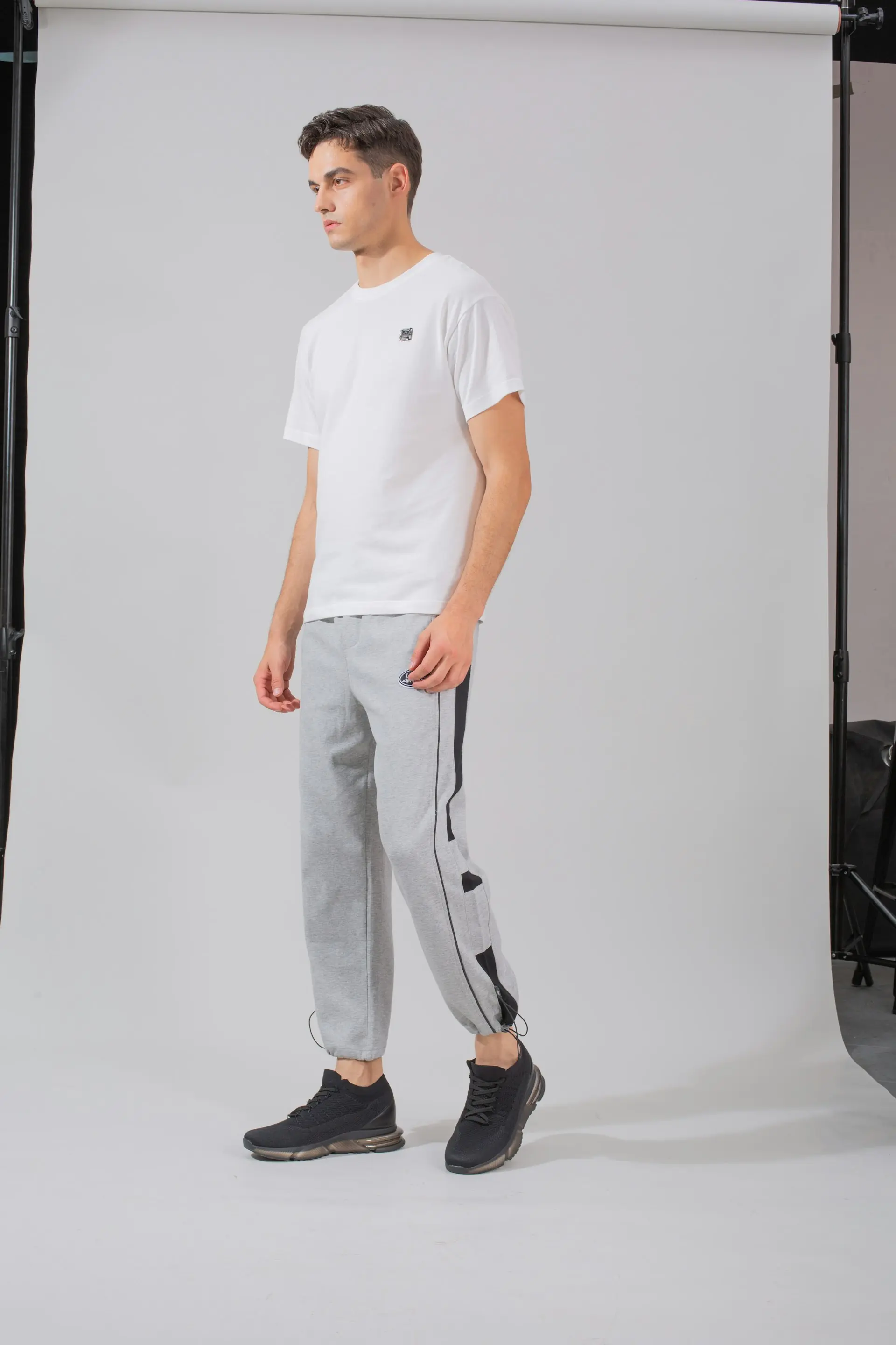 A man in joggers against a studio backdrop.