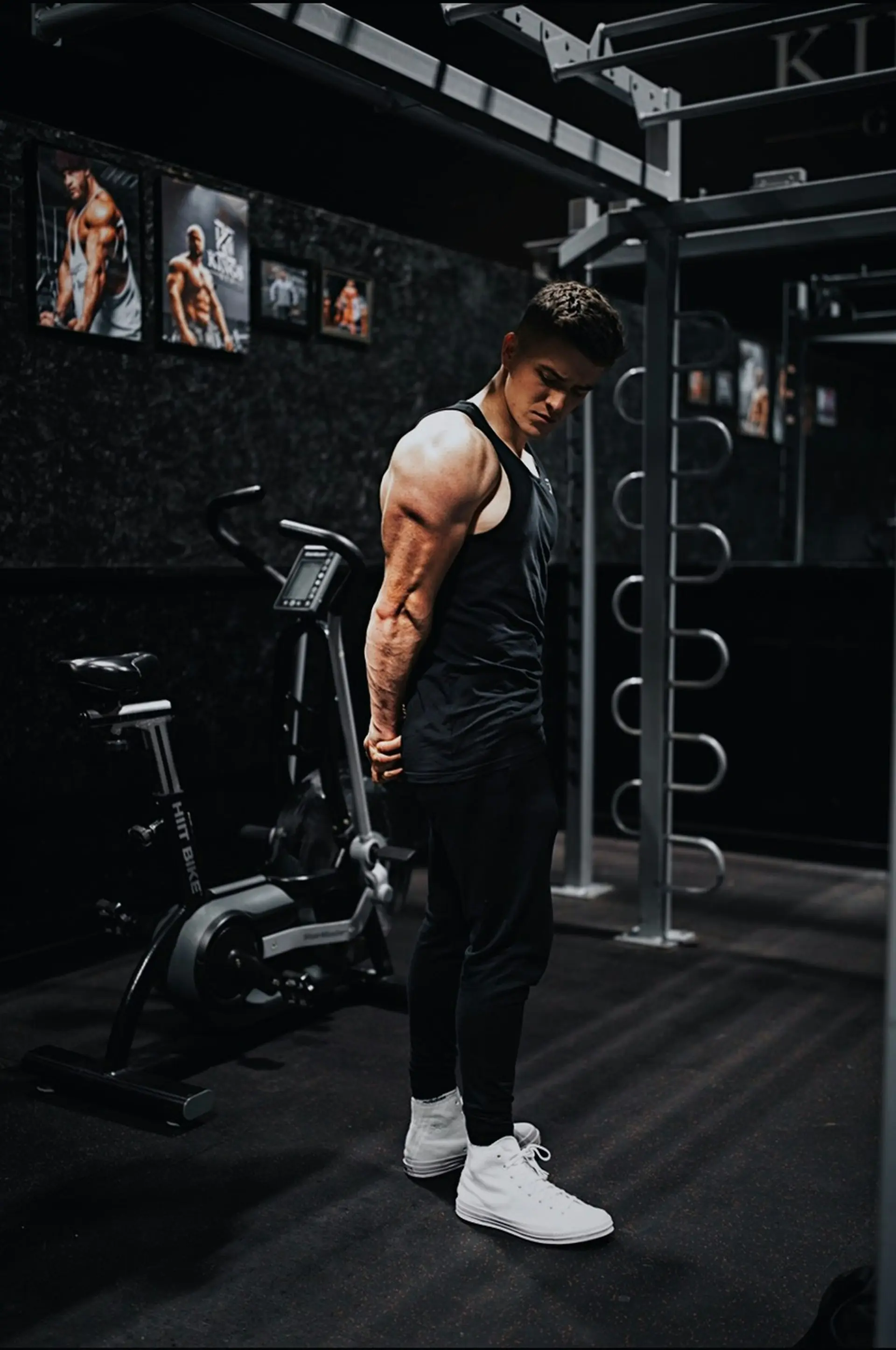 A lifter in black tank and pants on gym equipment.