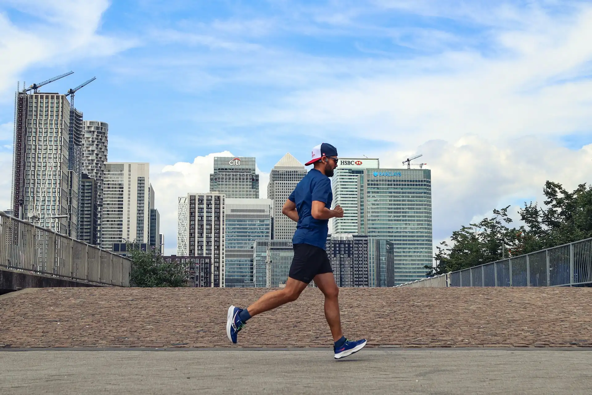 A man running through the city, tall buildings behind.