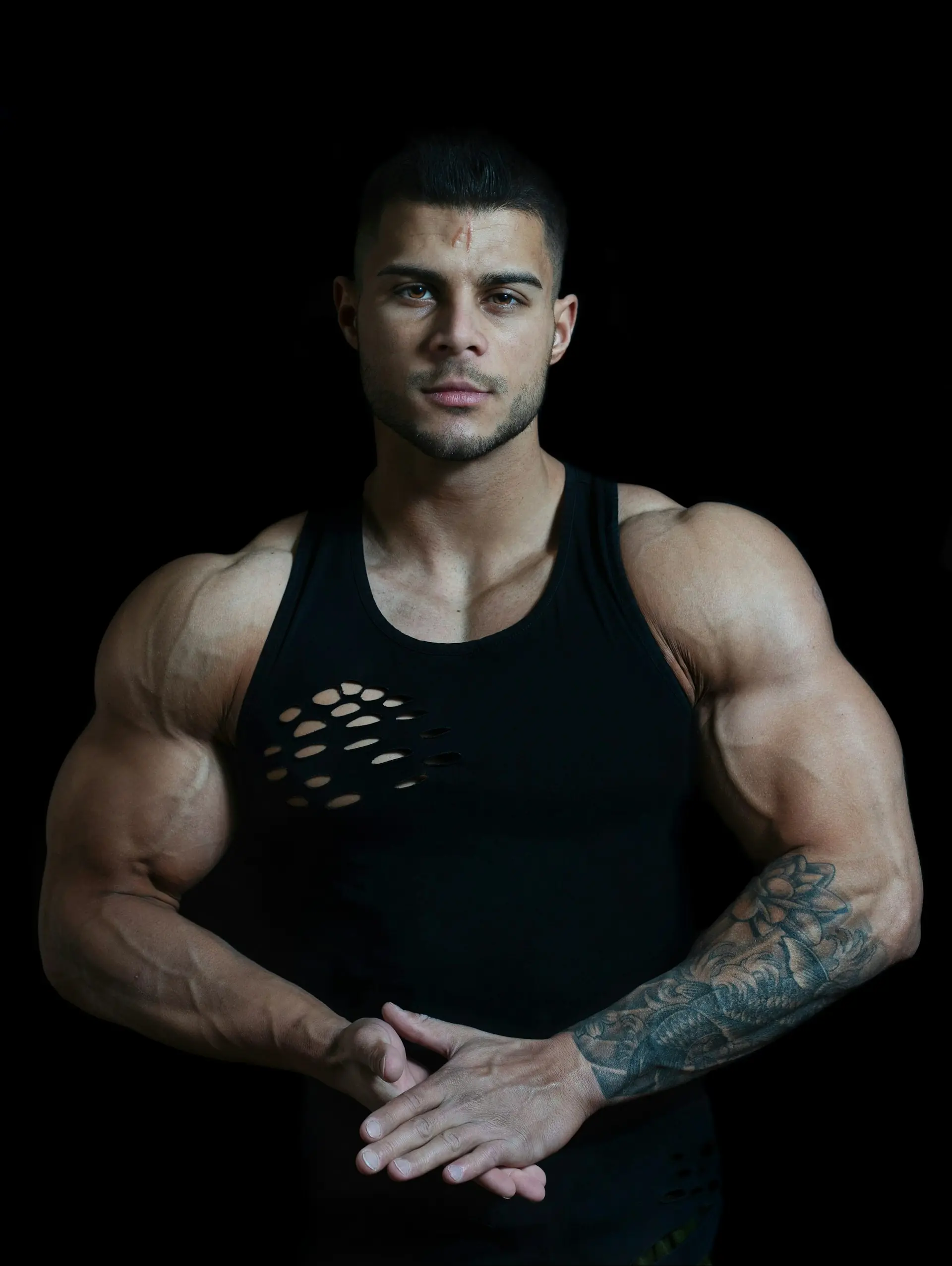 A man in a black cut-off tank, tattooed arm.