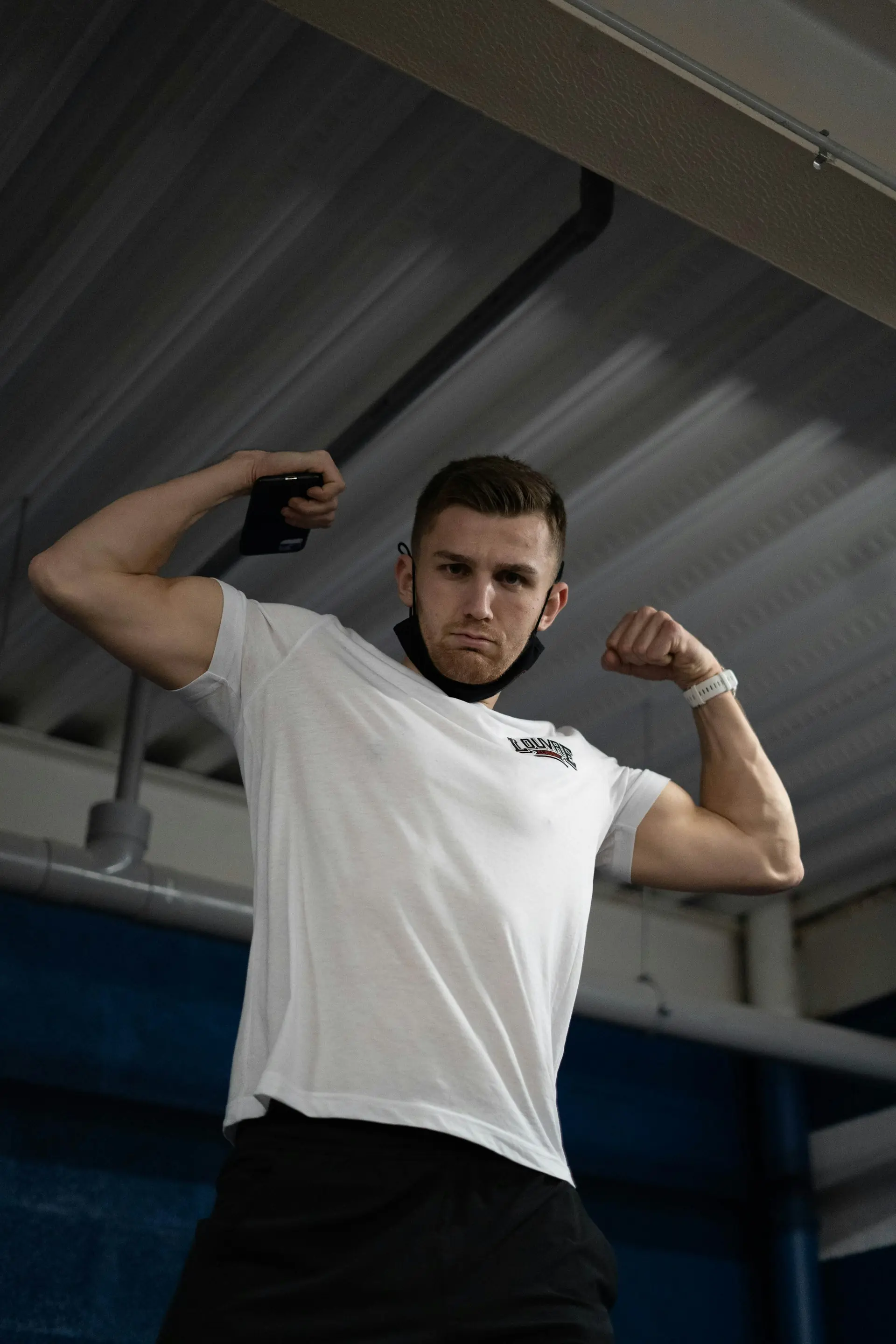 A man in a fitted white tee, arms tensed.