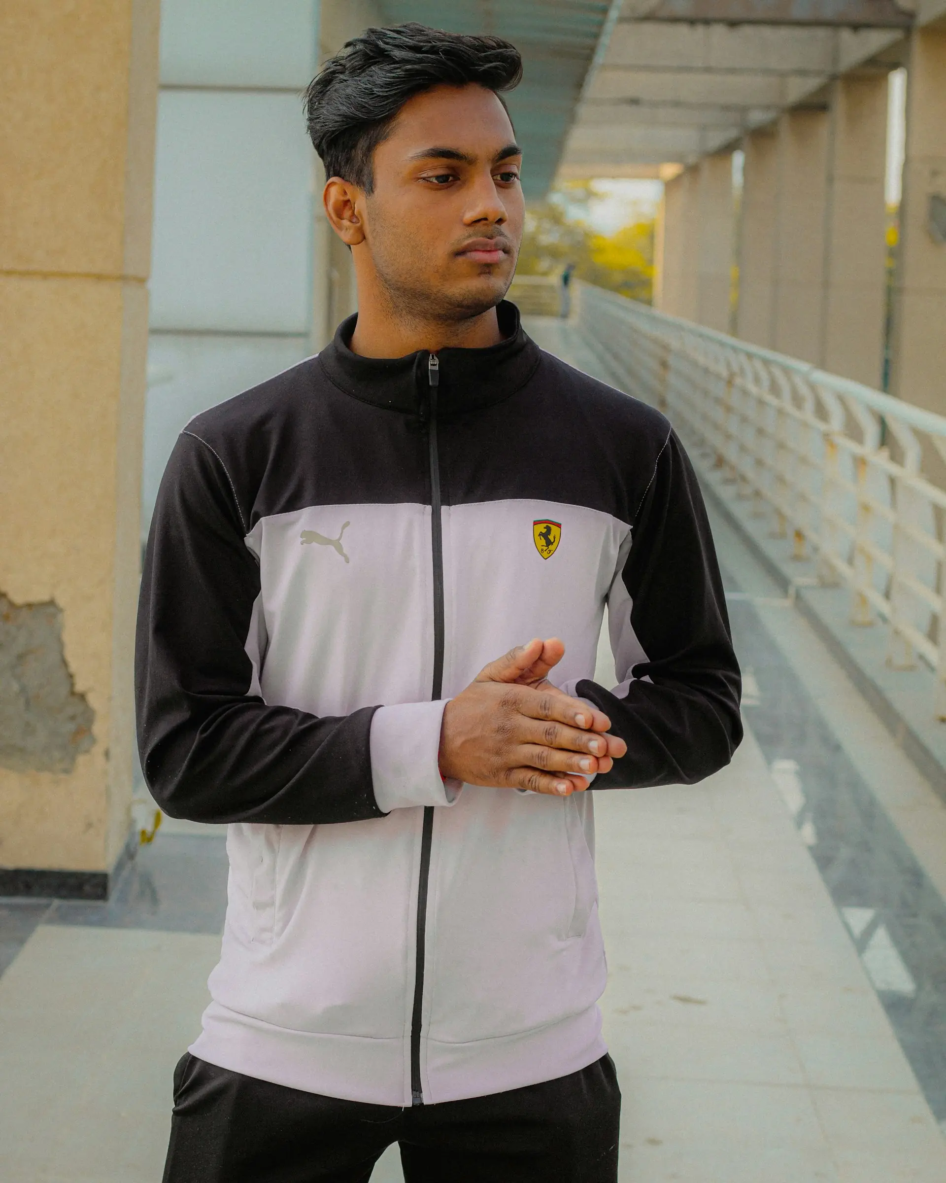 A man in a black zip track jacket on the street.