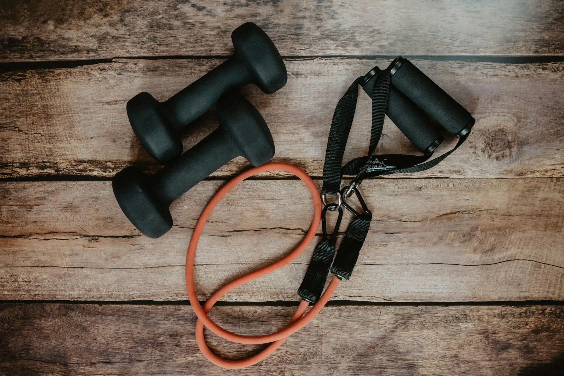 A resistance set and soft dumbbells arranged on rustic wood.