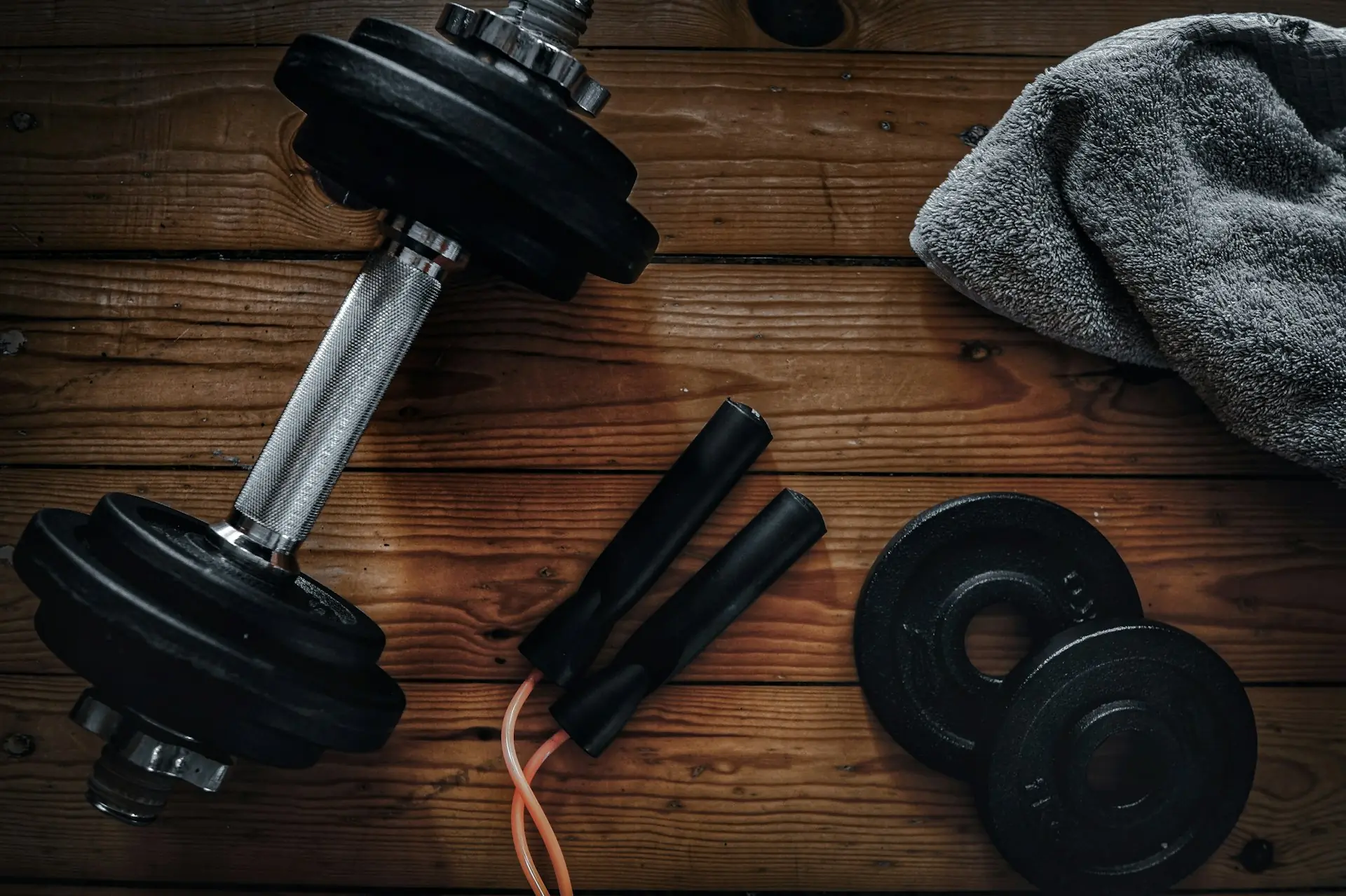 A speed rope coiled beside plates and a towel on warm boards.