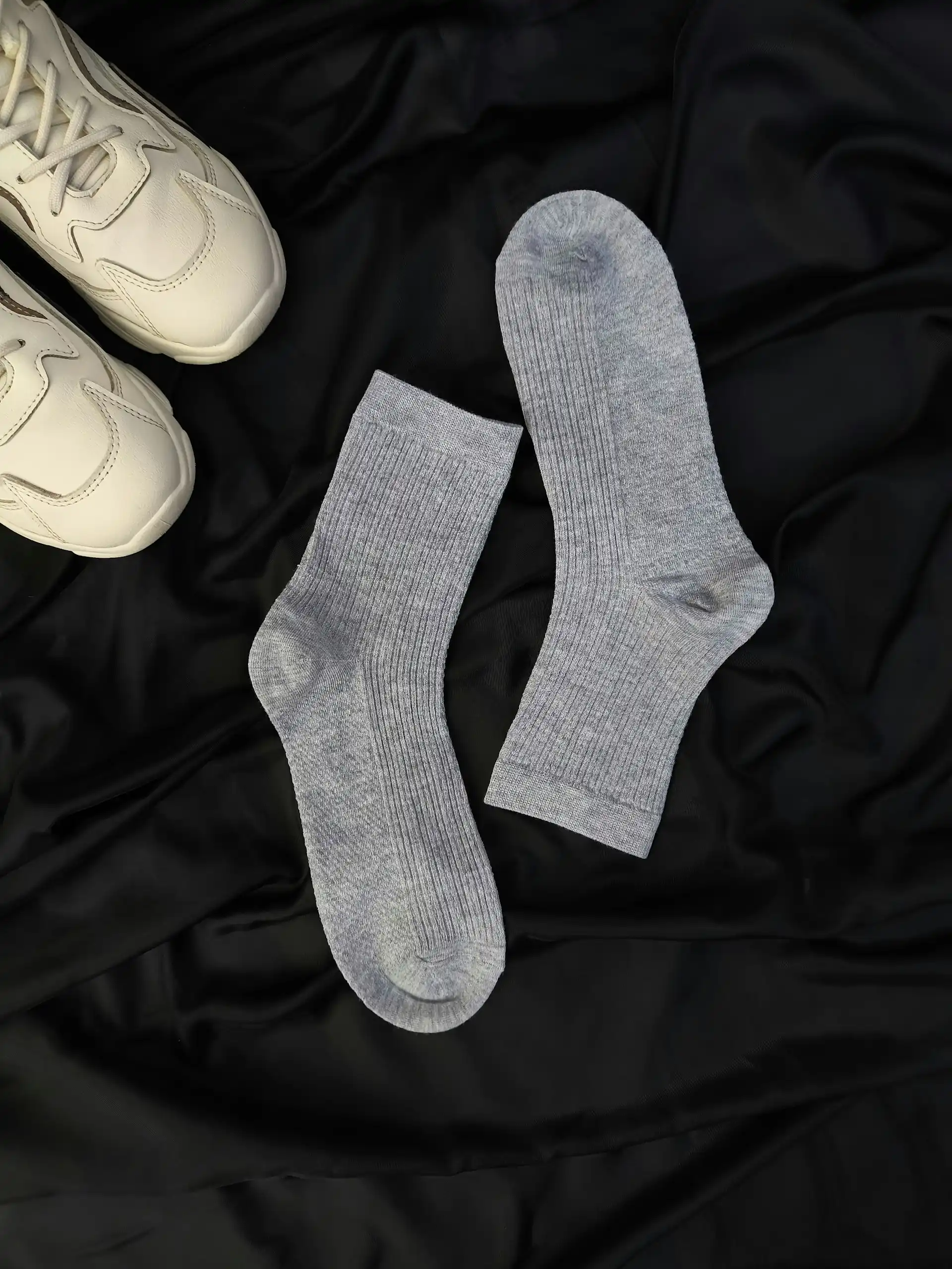 Grey performance crew socks laid on dark fabric.