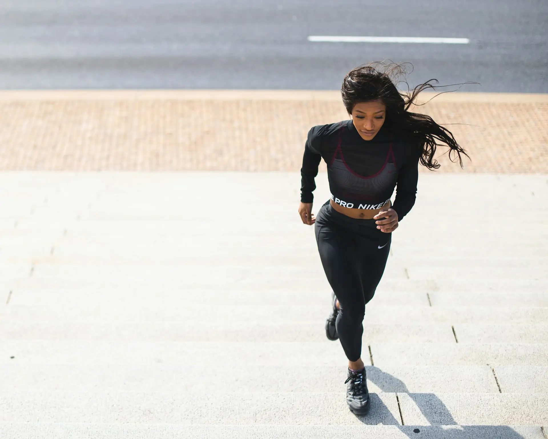 A woman running in a black long sleeve and tights.