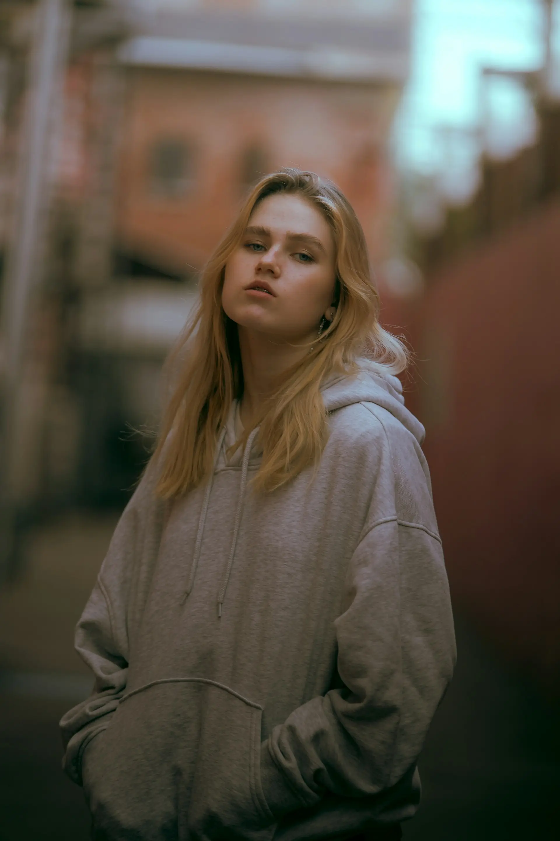 A woman in a grey hoodie against a red wall.