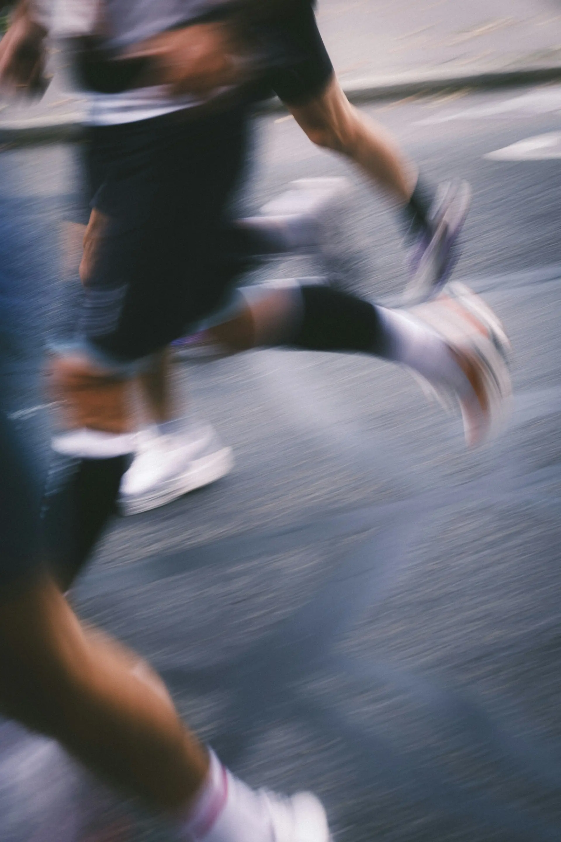 Runners mid-race, legs in motion blur on the road.